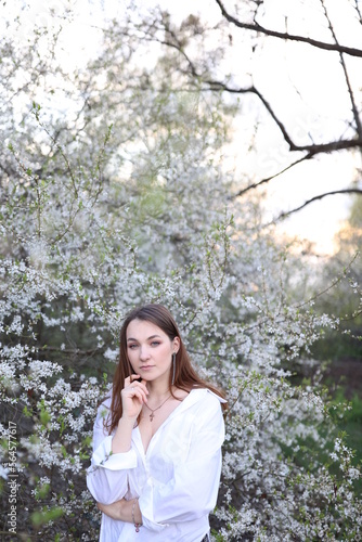 beautiful girl in a white shirt near a blooming tree. Beautiful warm spring and blossoming trees