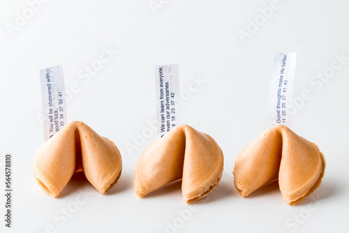 Photos Three crispy fortune cookies in a row with fortune notes inserted