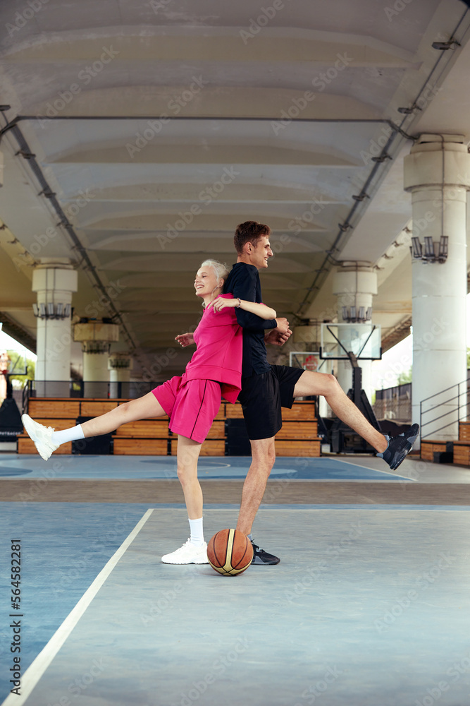 A guy and a girl are playing basketball on the city playground. Diversity man and woman play basketball. A guy and a girl are playing basketball on the city playground. Diversity man and woman play basketball.