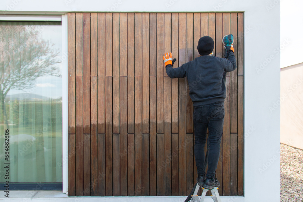 Wood worker professional sanding exterior teak hardwood facade cladding
