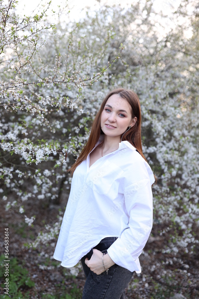 beautiful girl in a white shirt near a blooming tree. Beautiful warm spring and blossoming trees beautiful girl in a white shirt near a blooming tree. Beautiful warm spring and blossoming trees
