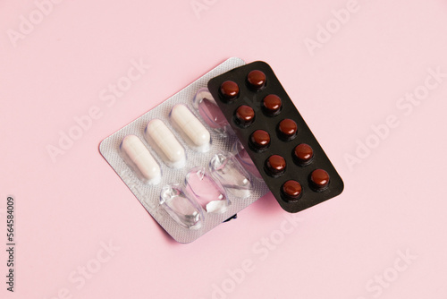 Pills in blisters on pink paper background with copy space, flat lay