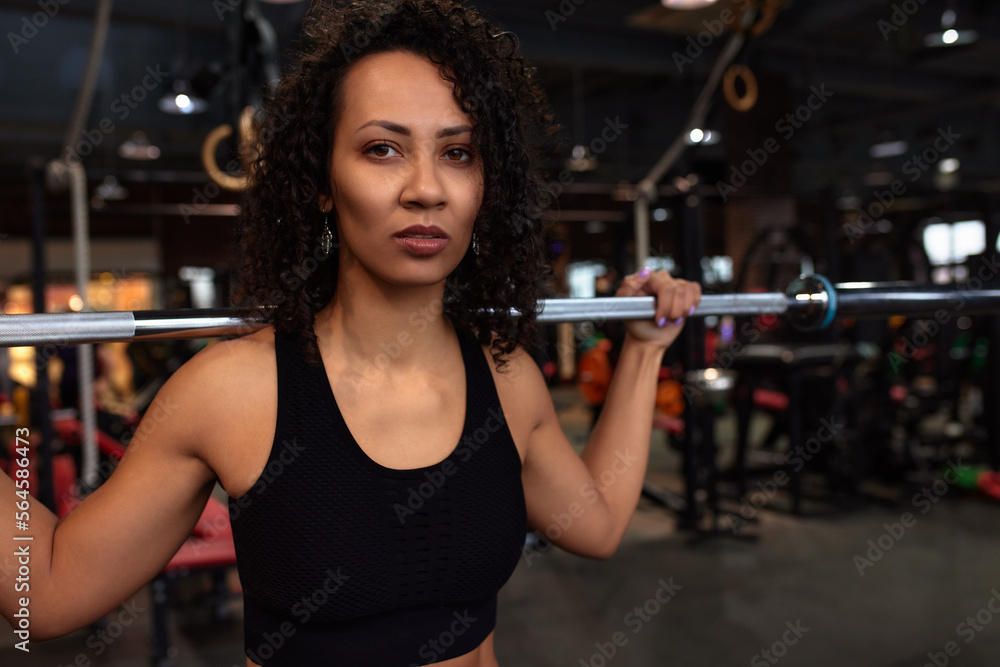 Sexy gorgeous african american woman working out with a barbell in the gym, copyspace, sports lifestyle, wrestling, be in good shape