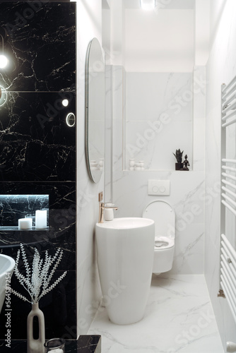 Spacious bathroom in black and white tones with heated floors, freestanding tub and sink