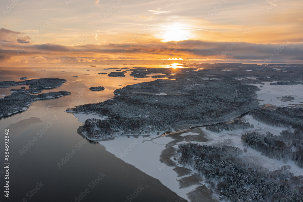 Naklejka premium Top view of the snow-covered Soukka Islands in Espoo. Sunset on a winter day. There is ice on the water in places. Winter landscape. Scandinavia.