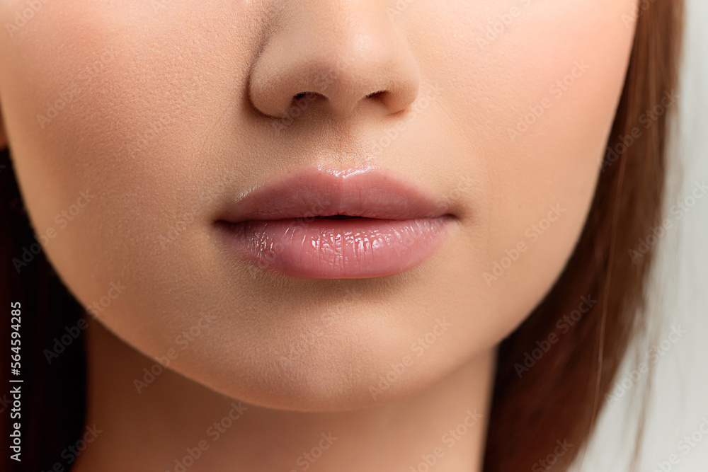 Cropped image of well-kept female face, nose and lips on grey background. Lip augmentation, moisturizing products. Concept of natural beauty, skin care, cosmetology, cosmetics, health, plastic surgery Cropped image of well-kept female face, nose and lips on grey background. Lip augmentation, moisturizing products. Concept of natural beauty, skin care, cosmetology, cosmetics, health, plastic surgery