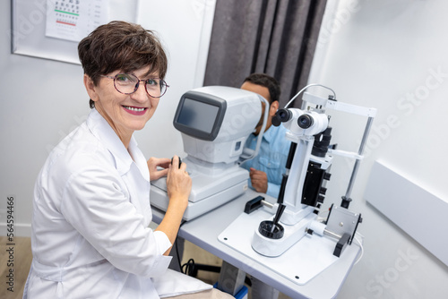 Optometrist in white scubs near refractometer photo