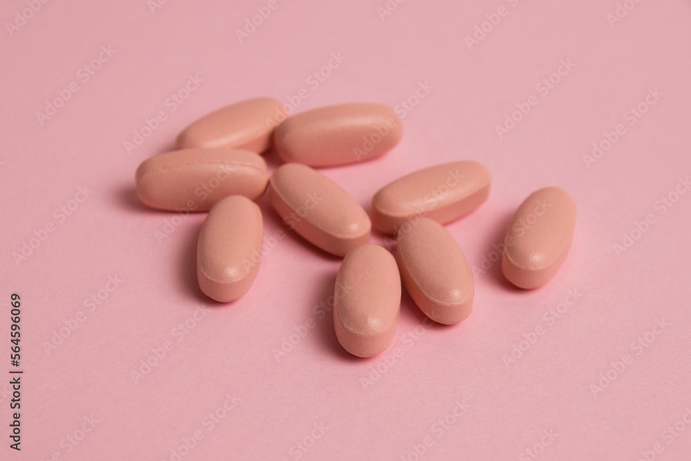 Pink pills on pink paper background with copy space. Concept of taking vitamins in pill form Pink pills on pink paper background with copy space. Concept of taking vitamins in pill form
