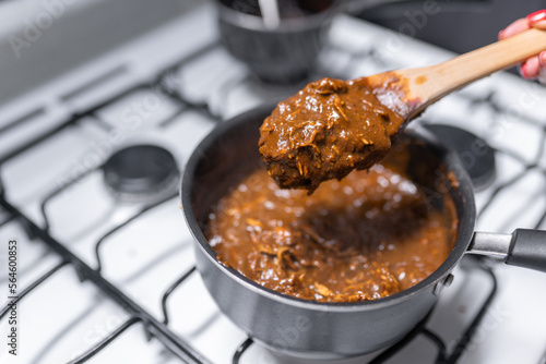 A young woman is cooking chicken with mole sauce using a gas stove photo