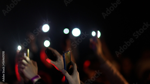 Fans Raise Hands and takes a photos in Front of Bright Colorful Strobing Lights on Stage.