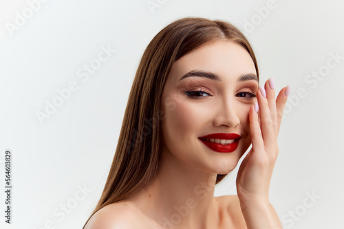 Tender make-up look. Young beautiful brunette girl with red lips makeup posing over grey studio background. Concept of natural beauty, youth, fashion, cosmetology, wellness, makeup.