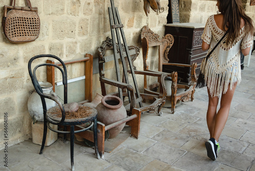 Canvas-taulu Woman tourist takes a stroll to a market featuring vintage furniture and decor items