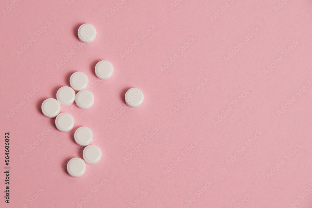 Flatlay, many white pills on a pink paper background Flatlay, many white pills on a pink paper background