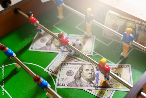 Table football game with US dollar bills scattered around it, alluding to a betting concept