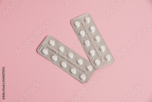 White pills in a blister on a pink paper background. Concept of treatment of diseases and support of the body in spring