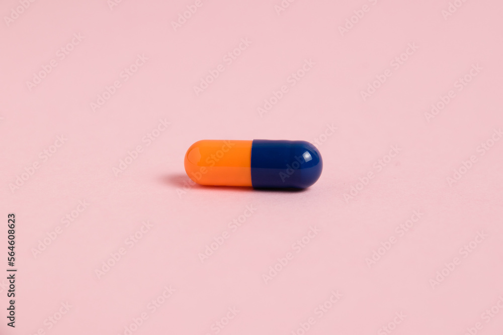 Multicolored pill on pink paper background with copy space, macro. Concept of treatment of covid 19 and colds.