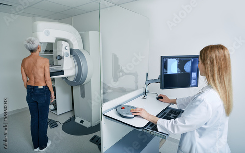 Mammogram procedure. Preventive diagnostic of senior woman by radiologist using mammography workstation to receive mammogram at radiology room