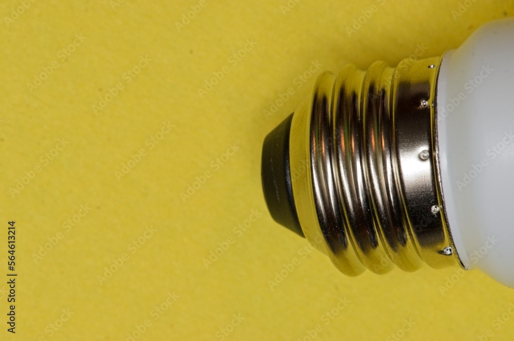 Metal screw base of a light bulb on a yellow background Metal screw base of a light bulb on a yellow background