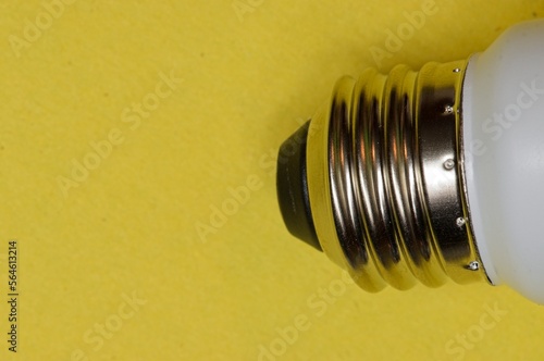 Metal screw base of a light bulb on a yellow background photo