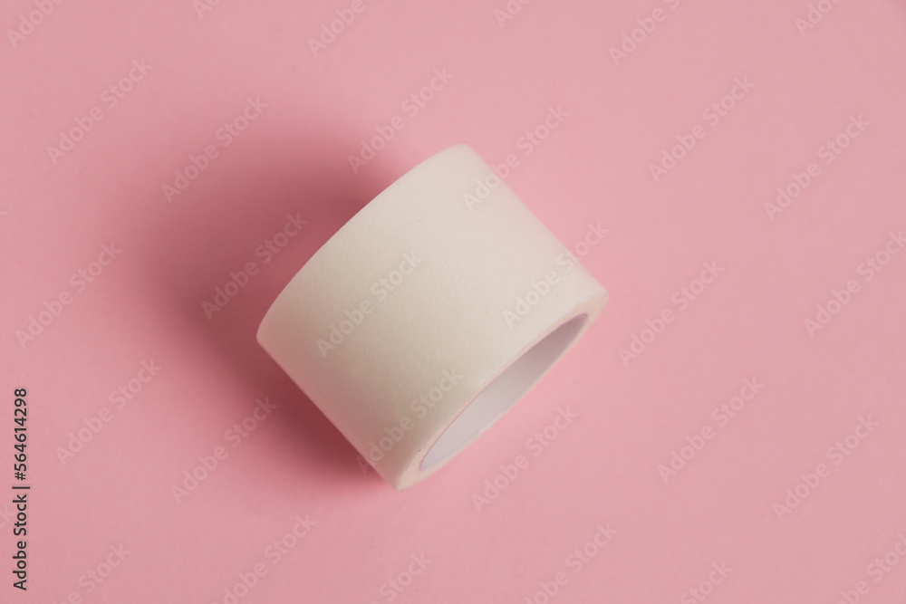 White medical patch on a paper base, for applying bandages, on a pink background White medical patch on a paper base, for applying bandages, on a pink background