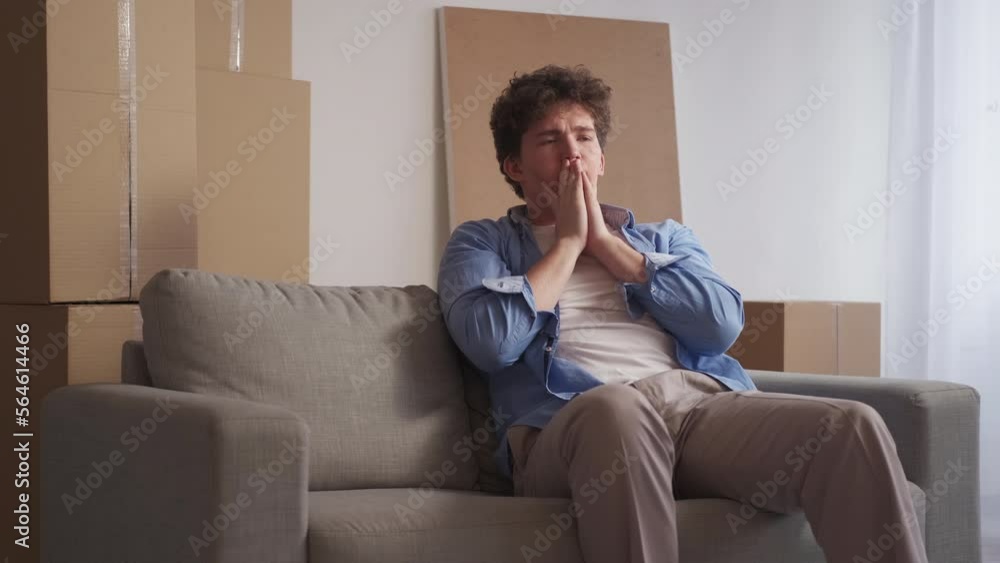 Move problem. Panic man. Nervous feelings. Worried frustrated guy expressing scared emotion sitting sofa with packed cardboard boxes light room interior. Move problem. Panic man. Nervous feelings. Worried frustrated guy expressing scared emotion sitting sofa with packed cardboard boxes light room interior.