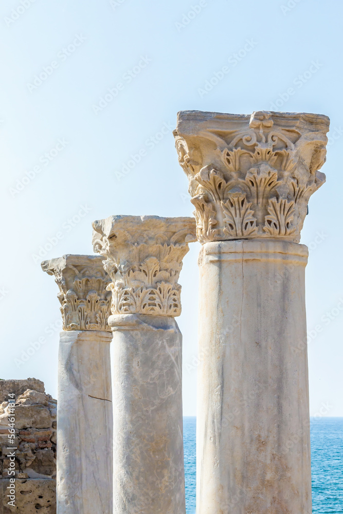 Corinthian capitals (partially ruined) and columns in Side city (Turkey) on promenade. Sea and blue sky at background. Copy space Design or art history concept