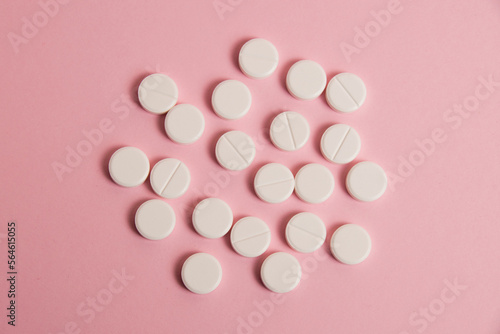 Flatlay, many white pills on a pink paper background photo