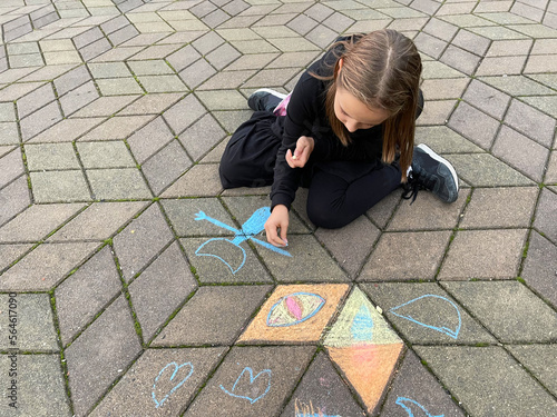 Child drawing painting on asphalt, imagination and leisure activity concept.