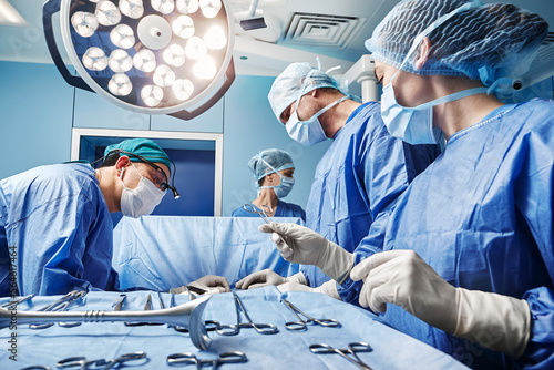 Bild auf Leinwand Surgical nurse giving surgical scissors to male surgeon during operation in operating theatre