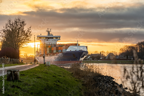 Nord Ostsee Kanal, Durchfahrt Containerschiff. Sonnenuntergang am Kiel Kanal mit Schiff. Der Kanal verbindet die Nordsee mit der Ostsee und verläuft durch ganz unterschiedliche Landschaften, Stadt. photo