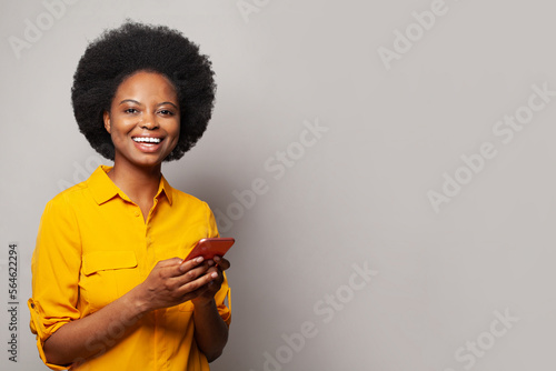 Сheerful cute beautiful young woman chatting by mobile phone isolated over grey wall background