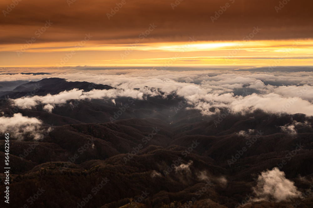 Obraz premium Sea of clouds over the mountains. Amazing sunset landscape over the foggy hills during an autumn day. Nature and travel aerial photos.