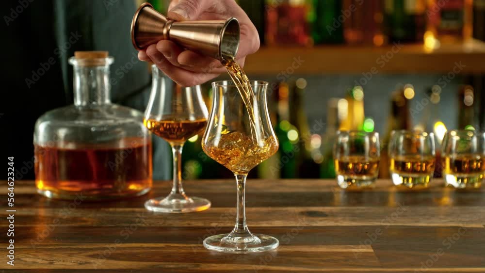 Super slow motion of pouring cognac into glass with speed motion. Filmed on high speed cinema camera, 1000 fps, placed on high speed cine bot. Bar with bottles on background. Super slow motion of pouring cognac into glass with speed motion. Filmed on high speed cinema camera, 1000 fps, placed on high speed cine bot. Bar with bottles on background.