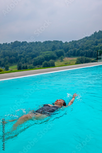 Woman Swimming in a Swimming Pool with Panoramic View with Mountain in Ticino  Switzerland.
