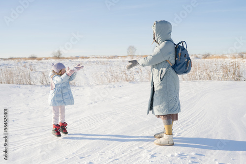 A young pregnant woman plays outdoors in winter, with a child