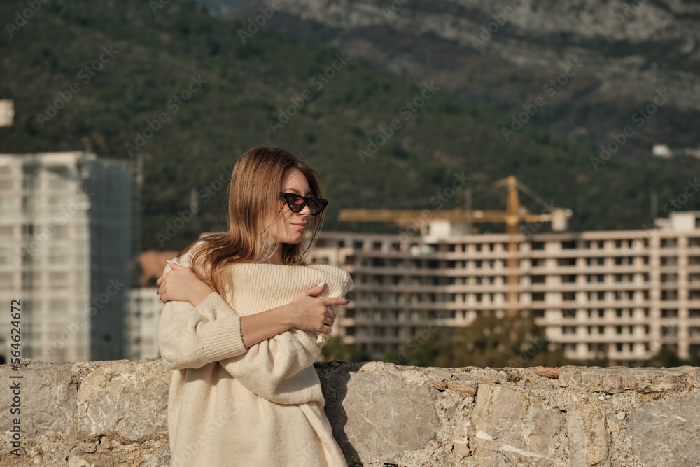 Fototapeta premium The girl crossed her arms over her chest, holds on to her shoulders and looks to the right
