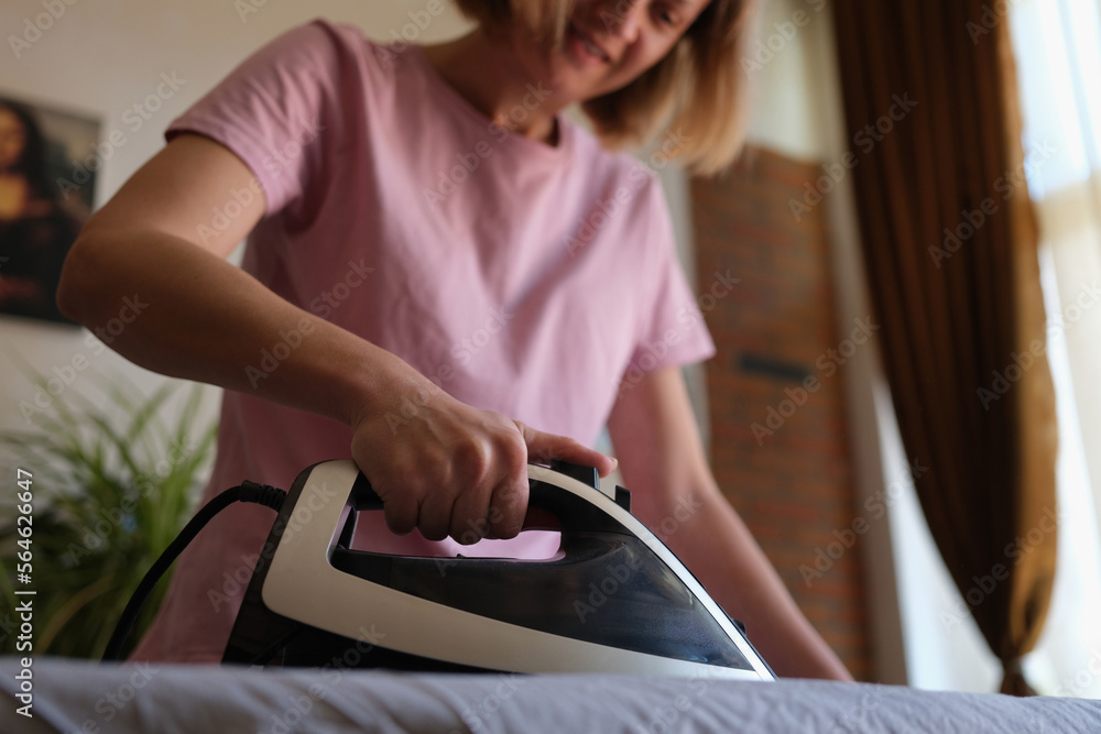 Woman ironing clothes at home on ironing board.