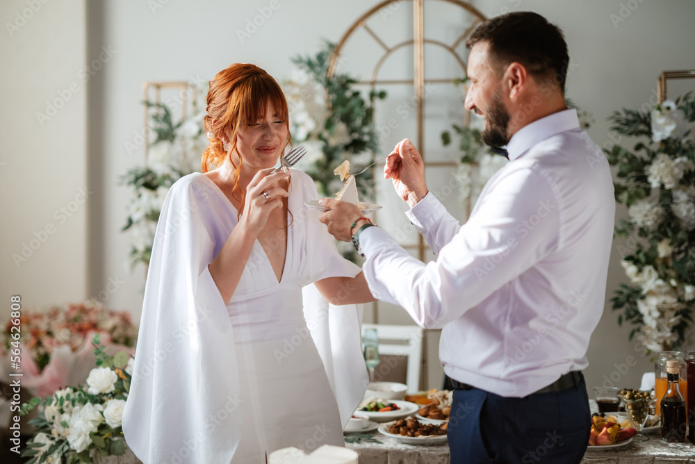 newlyweds happily cut and taste the wedding cake
