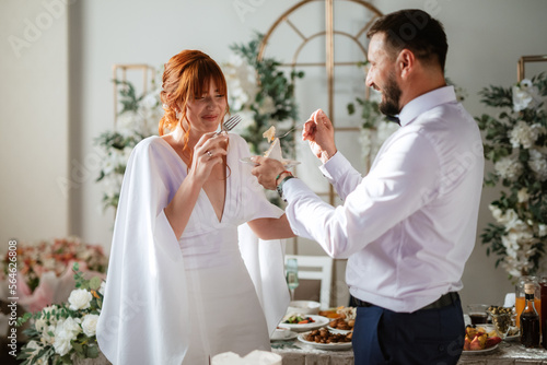 Obraz na płótnie newlyweds happily cut and taste the wedding cake w salonie
