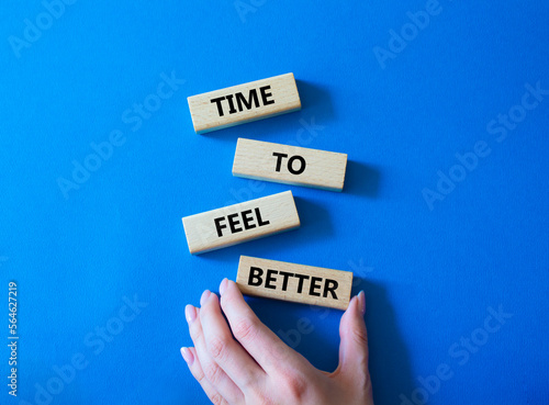 Time to feel better symbol. Wooden blocks with words Time to feel better. Businessman hand. Beautiful blue background. Medicine and Time to feel better concept. Copy space.
