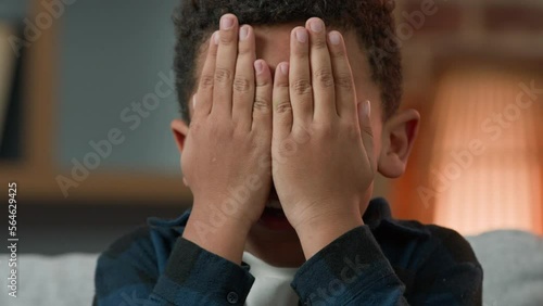 Close up happy playful little boy African American ethnic kid child son schoolboy schoolkid preteen baby funny pupil playing peek a boo game peek-boo play cover face with hands hiding hide and seek photo