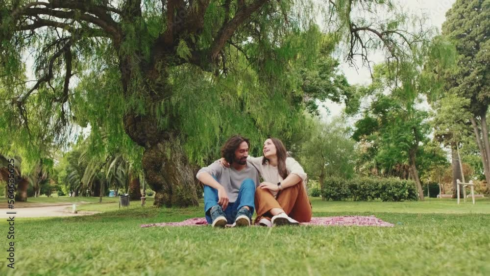 Couple talking while sitting on blanket at picnic in the park Couple talking while sitting on blanket at picnic in the park