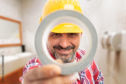 Close-up on smiling man worker holding duct-tape over his face