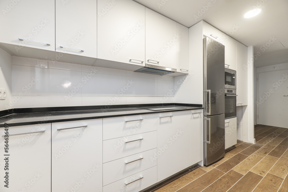 Newly installed white cabinet kitchen with integrated stainless steel appliances and black stone countertop Newly installed white cabinet kitchen with integrated stainless steel appliances and black stone countertop