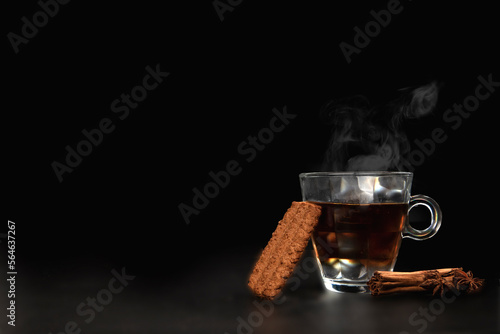 A glass of freshly brewed black tea,escaping steam,warm soft light, darker background. copy space