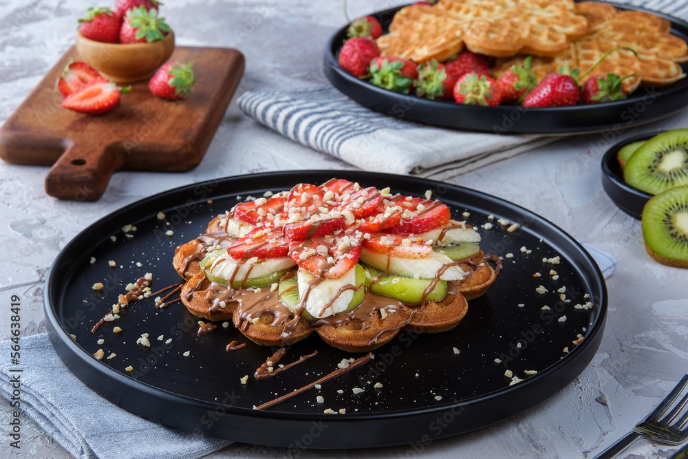 Homemade waffles with berries in plate on grey wooden table