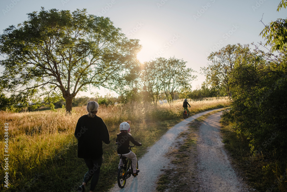 Mother teaching kid to ride bicycle on dirt road Mother teaching kid to ride bicycle on dirt road
