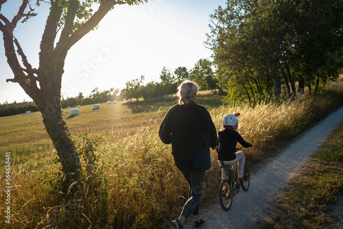 Mother teaching kid to ride bicycle on dirt road