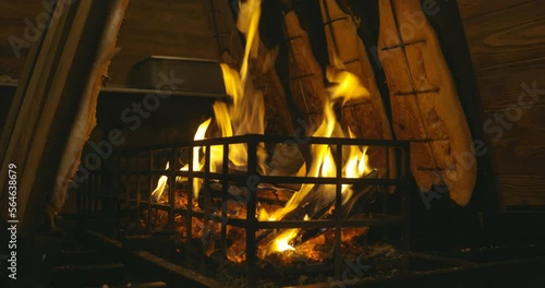 Leipzig, Germany - 12 03 2022: Salmon fish fillet grilled as flame salomon over a camp fire on a wooden salmon board. The fire burns in a metal cage. photo