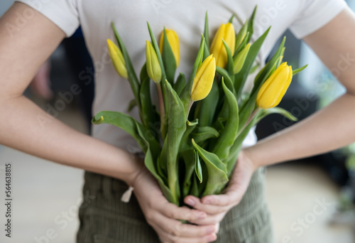 The girl has a gift for women behind her - yellow tulips